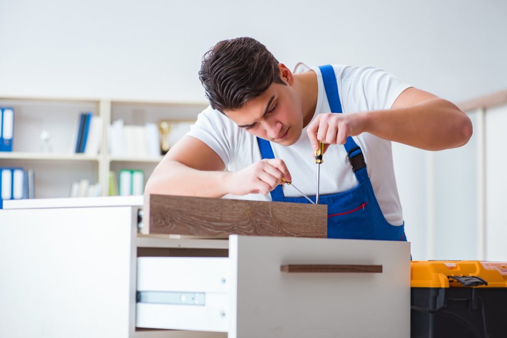 Furniture assembly technician carefully installing cabinet hardware with precision