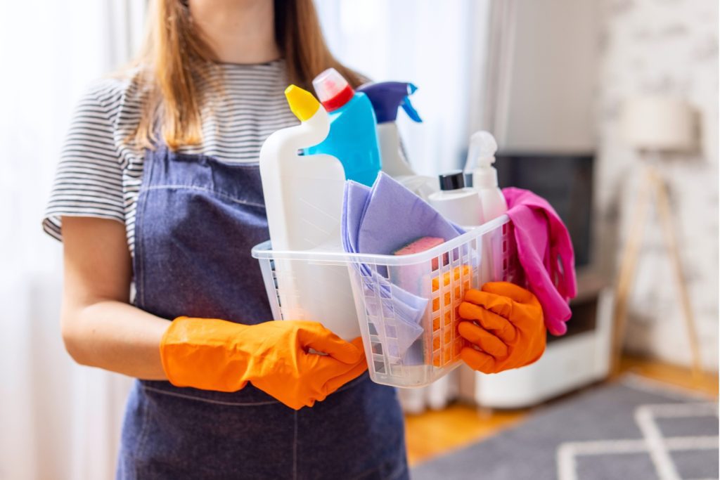 Professional cleaner holding a basket of cleaning supplies during a home cleaning service in Delaware County