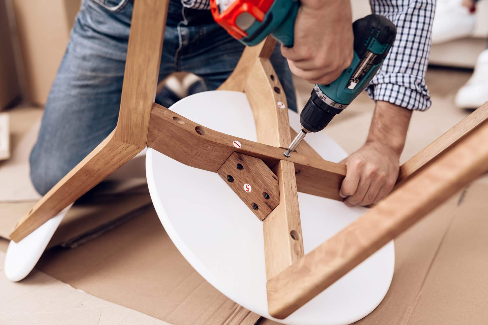Furniture assembler using a drill to build a wooden cabinet