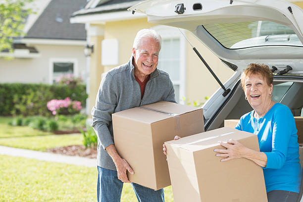 Senior movers helping an elderly couple move boxes during a home relocation